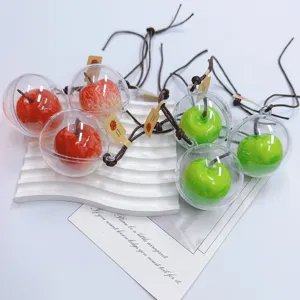 Detailed macro view of red and green faux apple ornaments in clear spheres on a tray