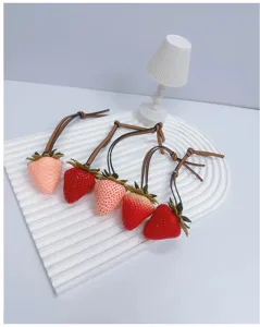 Detail view of five cute 3D simulation strawberry bag charms in various shades of red and pink