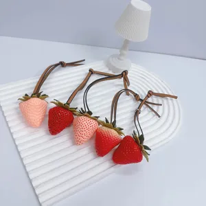 Realistic strawberry bag charms set for handbags and accessories with leather straps.