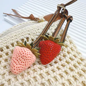 Pair of cute realistic strawberry bag charms in red and pink with leather straps