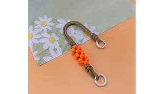 Detail of the braided paracord phone wrist strap with orange daisy flower designs.