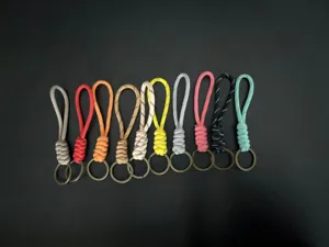 Set of ten colorful braided paracord keychains with vintage brass rings on black background