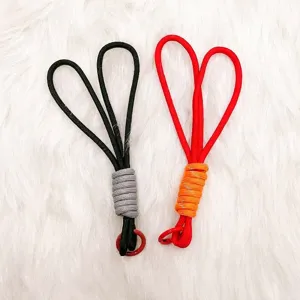 Pair of handmade woven paracord keychain pendants in black and red on white fur.