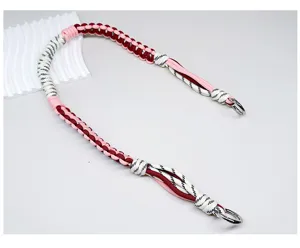 Detail van handgeweven gevlochten tasriem in roze en bordeauxrood met metalen ringen