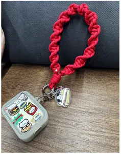 Primer plano de una correa de muñeca de paracord rojo trenzado con dijes animados.
