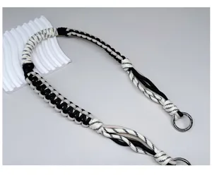 Gedetailleerd overzicht van handgevlochten zwart-witte paracord tasriem met metalen ringen.