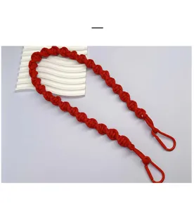 Detail view of hand-braided red rope bag strap with matching carabiner clips.