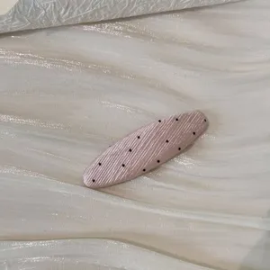 Vue détaillée de la pince à cheveux rose à pois avec une finition en tissu nervuré