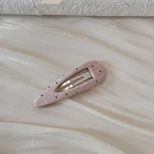 Gros plan macro d'une barrette à pois roses montrant le détail de la texture du tissu côtelé