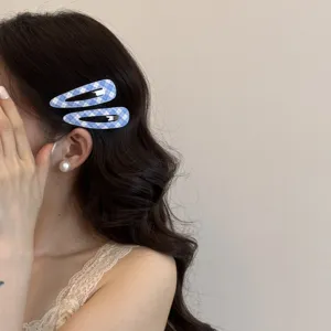 Dettaglio di graziose mollette per capelli a scacchi blu indossate su lunghi capelli mossi