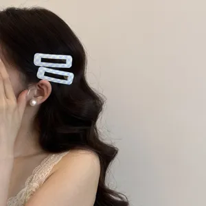 Primo piano di fermagli per capelli a quadretti azzurri su capelli scuri ondulati.