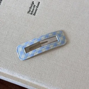 Vista macro dettagliata di una graziosa clip per capelli BB a quadretti su libro bianco