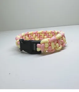 Detailed macro view of pink and yellow braided paracord bracelet with black plastic buckle