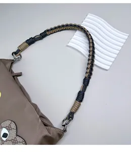 Dettaglio di tracolla in corda bicolore intrecciata a mano per borse con fibbie argentate.