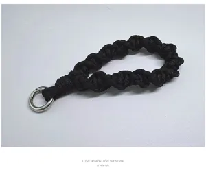 Detalle macro de correa de muñeca de macramé trenzado negro con aro plateado