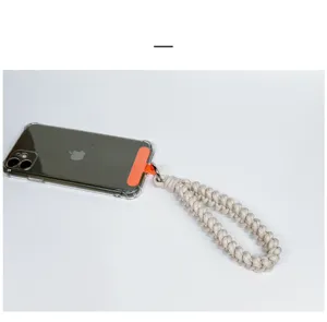 Detailed view of handcrafted beige woven phone wrist strap with orange connector tab.