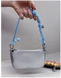 Macro view of a silver metallic mini handbag with light blue braided rope strap