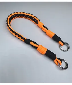 Dettaglio tracolla in paracord intrecciata arancione e nera con anelli metallici