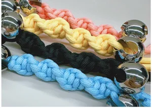 Close-up of colorful handmade braided bag straps with large metallic bead accents
