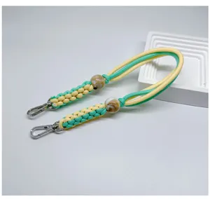 Détail d'un cordon de téléphone tressé jaune et vert avec perles marbrées et fermoirs
