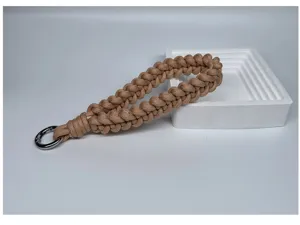 Detail view of a hand-woven paracord wrist lanyard with metal ring on a white tray