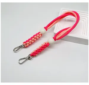 Gros plan d'un cordon de téléphone tressé rose avec des perles blanches et des fermoirs