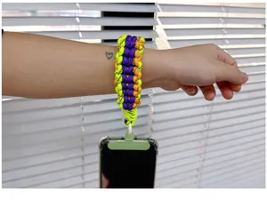 Handgefertigte geflochtene bunte Handy-Handschlaufe am Handgelenk mit Smartphone