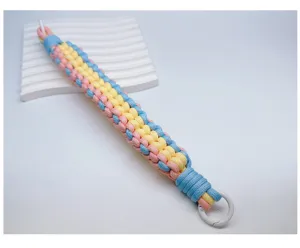 Detailansicht der handgewebten Handschlaufe in den Farben Pastellrosa, Gelb und Blau.