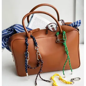 Colorful braided nautical rope bag charms with metal carabiners shown on a brown leather bag