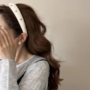 Close-up of a sweet white fabric headband with a delicate red cherry embroidery pattern