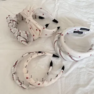 Detailed view of diverse white fabric hair hoops set with red cherry and stripe patterns