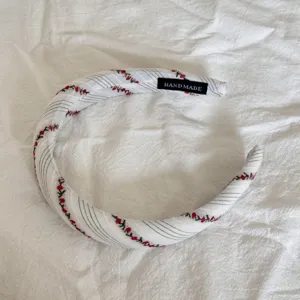 Close-up detail of a sweet fabric headband featuring red cherry and stripe patterns