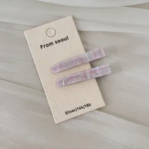 Gros plan sur deux barrettes à cheveux roses à motifs sur un support en carton