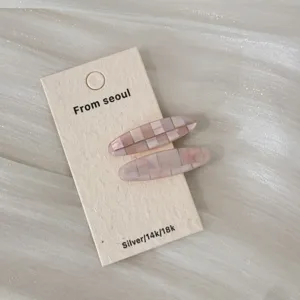 Gros plan de barrettes ovales roses élégantes à motif à carreaux sur carte support