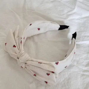Sweet white fabric headband with cherry print and large bow detail for girls daily wear