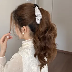 Detailed view of a white pleated satin banana clip accessory worn on a brown ponytail