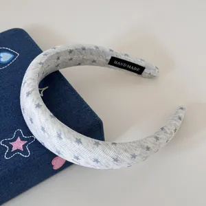 Vue détaillée d'un serre-tête en tissu rembourré gris clair avec étoiles et étiquette fait main