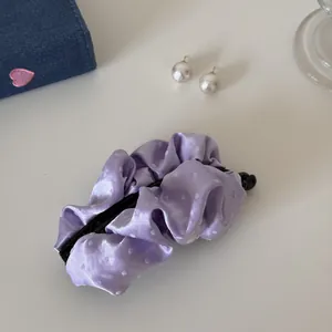 Detailed close-up view of a lavender satin polka dot banana hair clip on a white table