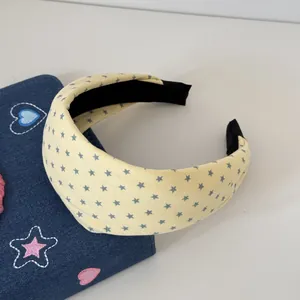Gros plan d'un serre-tête rembourré jaune crème avec motif d'étoiles mignon