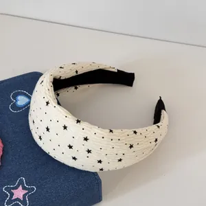 Détail du serre-tête rembourré crème avec motif d'étoiles noires et tissu texturé.