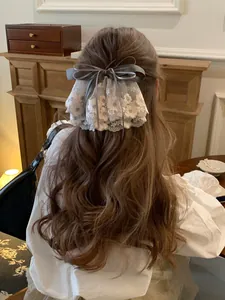 Vue détaillée d'une pince à cheveux à nœud gris avec une bordure en dentelle rose.