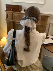 Détail d'une barrette à cheveux nœud gris et dentelle florale sur une tresse