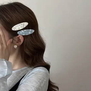 Vue latérale d'un mannequin portant deux barrettes à fleurs en tissu bleu et blanc.