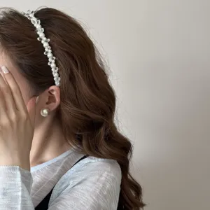 Detailweergave van een elegante parel hoofdband en bijpassende oorbel op een model