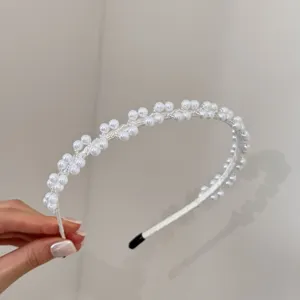 Detailopname van een elegante haarband met witte kralen en stoffen omwikkeling