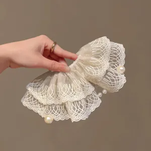Macro detail of French vintage cream-white lace scrunchie with elegant pearl accents