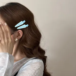 Gros plan détaillé de deux pinces à cheveux bec de canard bleu clair sur cheveux ondulés