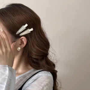 Gros plan de barrettes à cheveux crème et d'une boucle d'oreille en perle