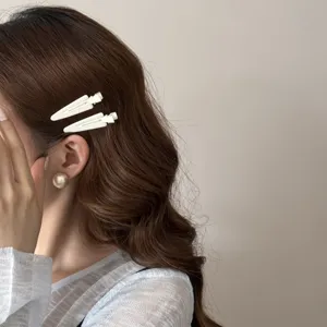 Gros plan de barrettes à cheveux triangulaires blanches sur les cheveux bruns ondulés