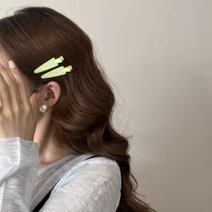 Gros plan de barrettes à cheveux triangulaires vert clair sur des cheveux bruns